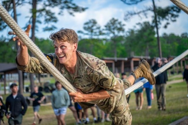 Sgt. Matthew Dunphy with Team 40 representing the 75th Ranger Regiment pulls himself along a rope during an obstacle course.